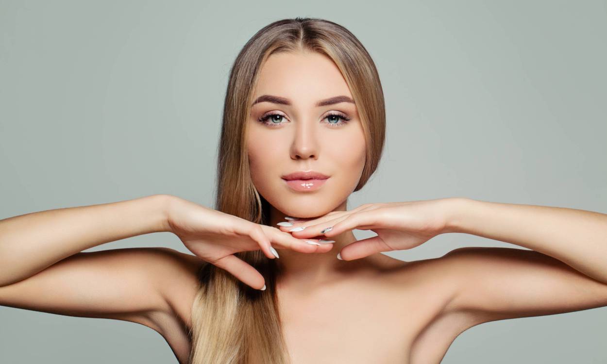 Young adult woman with long healthy straight hair and perfect clear skin. Pretty model girl face. Facial treatment, cosmetology, hair and skin care concept